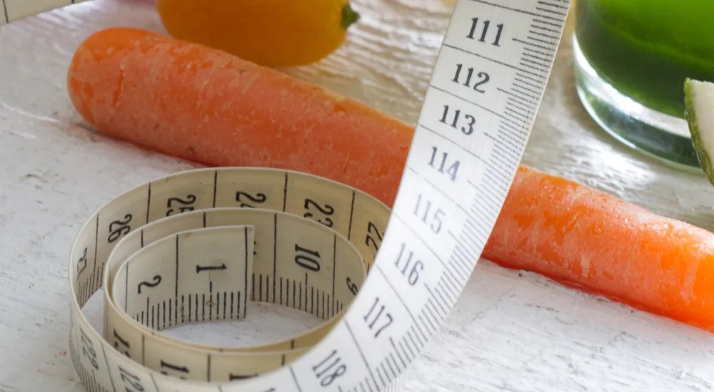Avoid the most common mistakes when losing weight and achieve your goals – carrot and measuring tape on a table